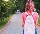 Rear view of a girl at green park. She has pink colored hair and shirt and wearing blue jeans