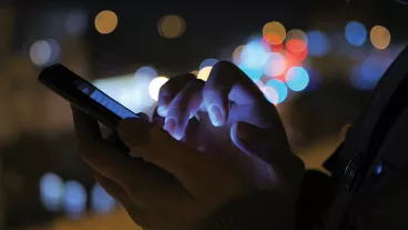 Close-up shot of woman hands with smartphone in the city at night.